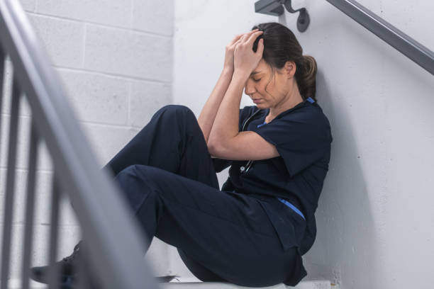 exhausted nurse sitting in hospital corridor - nurse hygiene emotional stress surgeon imagens e fotografias de stock