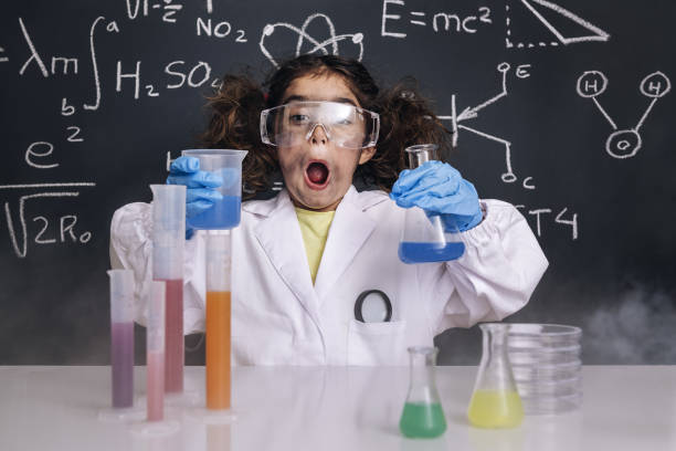 niño científico sorprendido en el abrigo de laboratorio con matraces - child discovery surprise playing fotografías e imágenes de stock