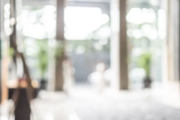 Photo of Hotel or office building lobby blur background interior view toward reception hall, modern luxury white room space with blurry corridor and building glass wall window