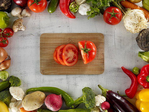 : Healthy food. Vegetarian Food. Tomatoes and peppers on a bamboo cutting board, on a black kitchen counter.