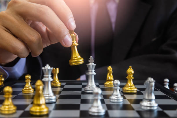 istock Chess game on chess board behind business man background. Business concept to present financial information and marketing strategy analysis. Investment target in global economy and digital commercial. 1216293513