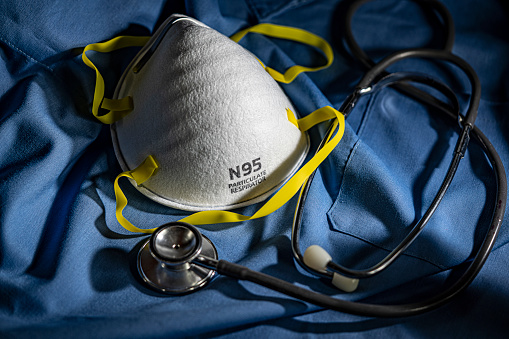 Close-up of Protective N95 Mask on Blue Scrubs with Stethoscope