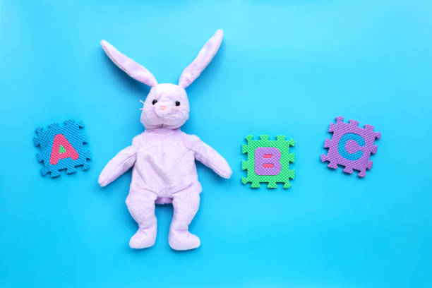 istock Rabbit toy with english alphabet puzzle on blue background. Education concept 1216307922