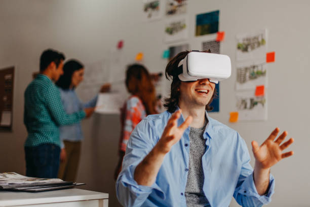 Man using virtual reality glasses in design office studio next by coworkers
