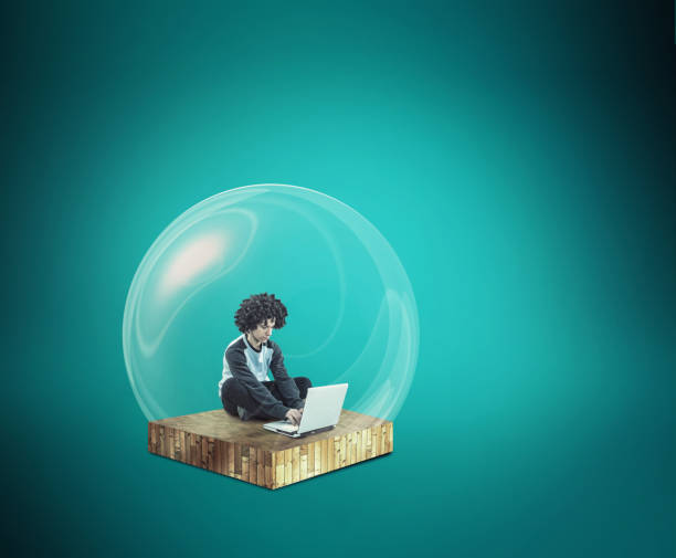 istock Social distancing and self-isolation during corona virus quarantine. Work from home concept . Man working online on a laptop inside a bubble protection shield . 1216314292