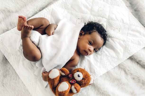 Portrait of cute adorable little african american baby sleep in a white bedroom stock photo