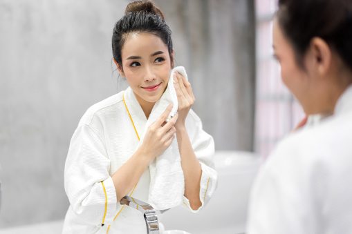 Beautiful young asian woman washing clean face with water and smiling in front of the mirror in the bathroom.beauty and spa.perfect fresh skin