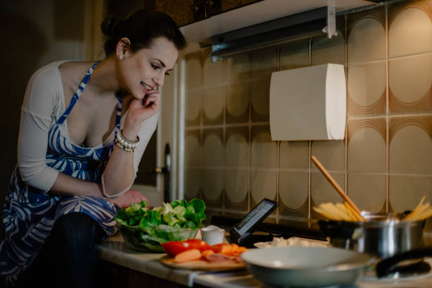 istock Woman reading recipe on digital tablet and preparing spaghetti 1216317807