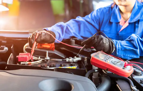 Asian technician measure voltage of battery in the car at service station, Maintenance and repair