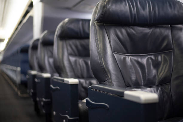 Rows of empty leather first class seats on a commercial airplane.