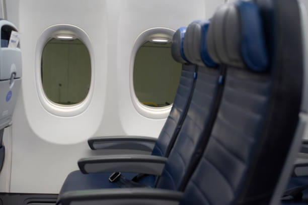 istock Airplane windows with blurry blue leather airplane seats in the foreground 1216319320