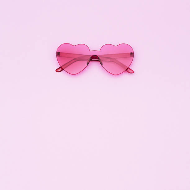 Creative top view with modern sunglasses on paper background. Heart shaped eyeglasses pink colored. Minimal summer concept. Flat lay with copy space.