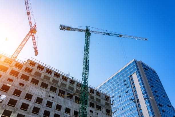 istock Bottom view of a building under construction with high construction cranes and a glass tower in the background. 1216322587