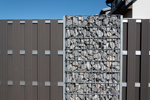 A gray gabion fence protects against prying eyes on the roadside in Bünde, East Westphalia