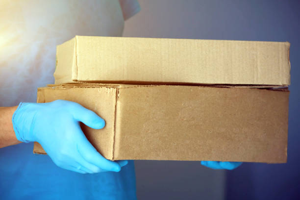 istock Male hands in blue rubber gloves hold a cardboard box. 1216328273