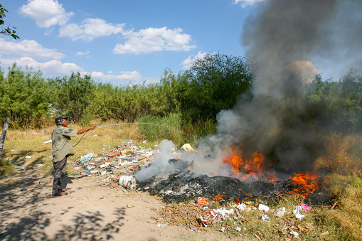 Piedras Negras, Mexico, September 28 -- A man burns out the trash in the town of Piedras Negras, near the boundary between the state of Coahuila in Mexico and Texas in the United States.