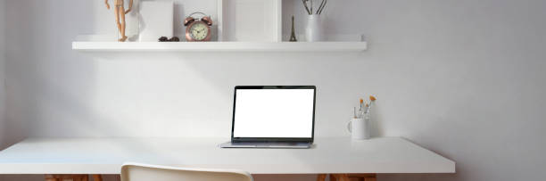 istock Cropped shot of minimal workspace with blank screen laptop and copy space with decorations on white shelf 1216330038