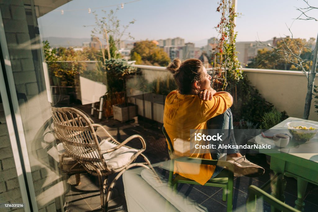 Enjoying spring on my balcony Photo of a woman drinking first morning coffee, eating 'take out' food and reading daily news online - on the balcony of her apartment while enjoying springtime sun Balcony Stock Photo