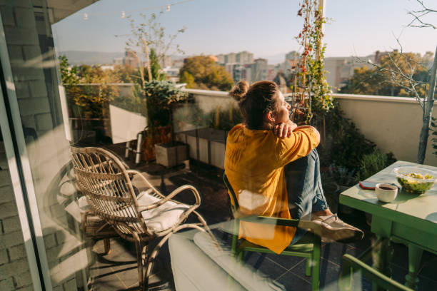 Enjoying spring on my balcony Photo of a woman drinking first morning coffee, eating 'take out' food and reading daily news online - on the balcony of her apartment while enjoying springtime sun balcony stock pictures, royalty-free photos & images