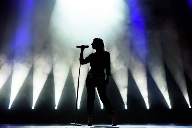 istock Vocalist singing to microphone. Singer in silhouette 1216331942