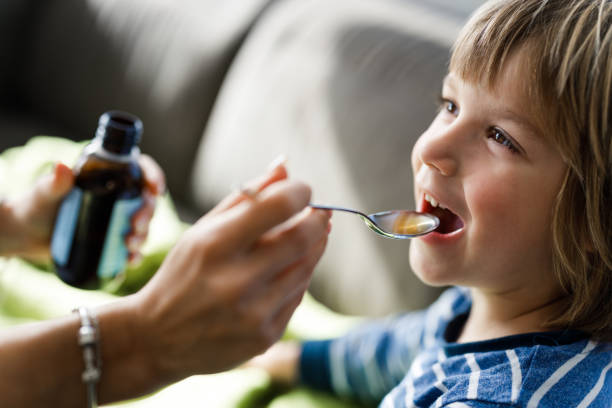 istock Happy boy taking cough syrup from his parent at home. 1216333329