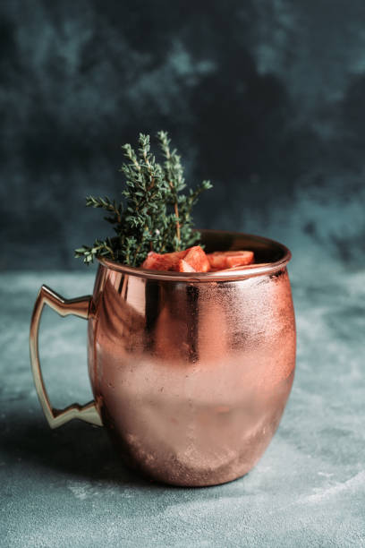 istock Red oranges cocktail in copper mug (variation of Moscow mule) on the wooden background 1216335792