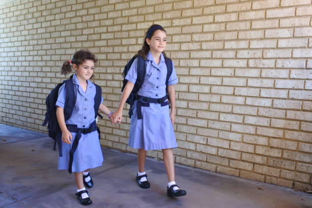istock Two sisters are holding hands going to school together 1216337626