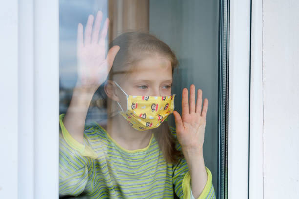 istock A little girl is on the window and looks out while she is in quarantine 1216338506