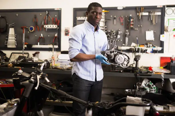 Portrait of man master who is repairing motobike in the workshop