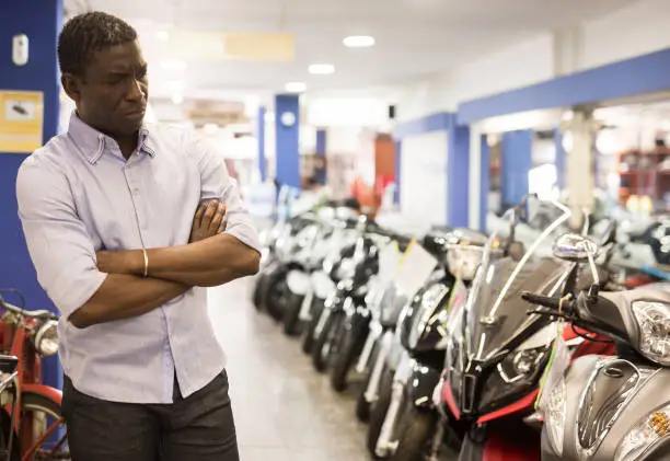 Afro american man is shopping and choosing new motobike in moto store