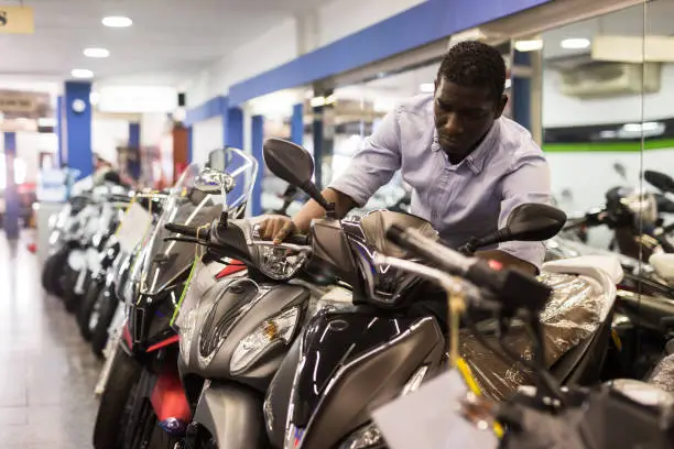 Afro american man is shopping and choosing new motobike in moto store