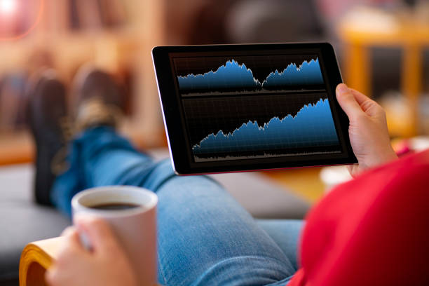 Young unrecognizable woman, wearing a jean, sitting on a couch and using a tablet computer.