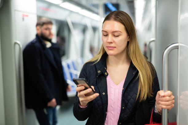 istock Young woman browsing on phone in metro car 1216344964