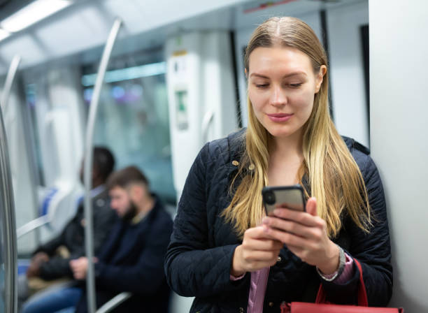 istock Young woman browsing on phone in metro car 1216344973