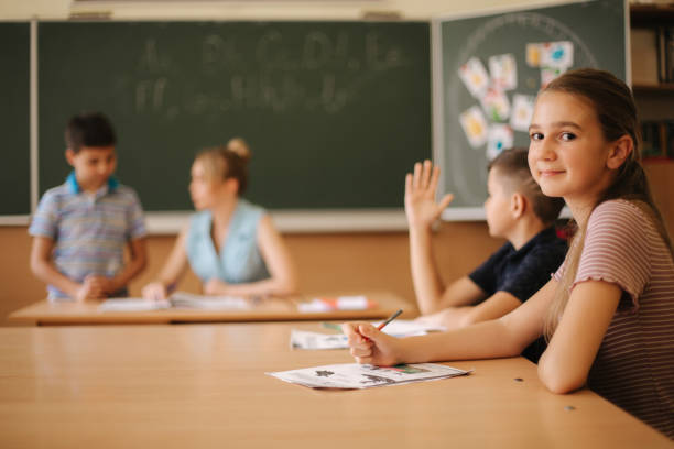 istock Education, elementary school. Learning and people concept - group of school kids with pens and notebooks writing test in classroom 1216346508