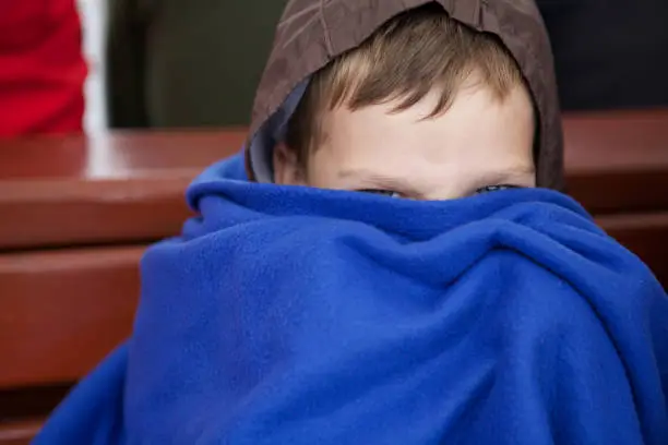June 29, 2013 - Norway: head of a small boy hiding under a blue blanket only eyes visible, face obscured