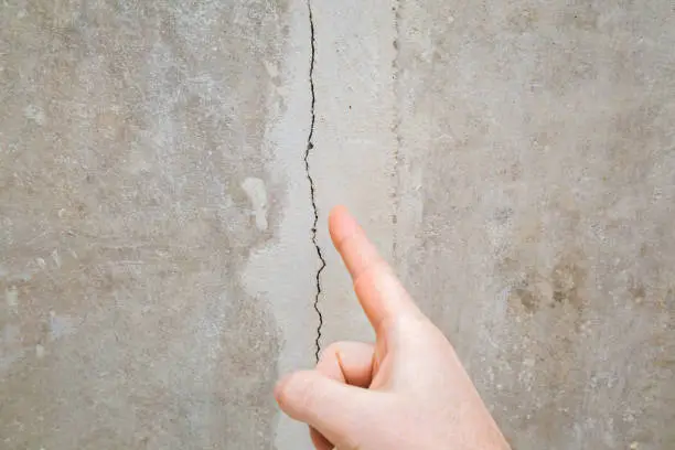 Man hand finger pointing to cracked ceiling. Building problem and solution concept. Closeup.