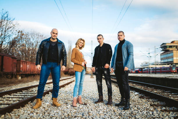 Four young Caucasian people having a walk on a railroad track.