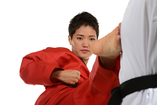 Martial artist focused executing a roundhouse kick on her training mannequin.