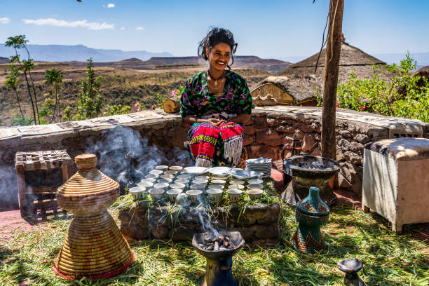 에티오피아 라리벨라: 전통 의상을 입은 젊은 여성이 커피 의식을 준비하고 있다. - ethiopian coffee 뉴스 사진 이미지