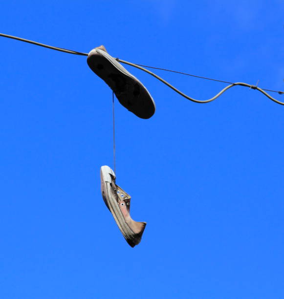 istock Shoes hanging on a line against a blue sky 1216351089