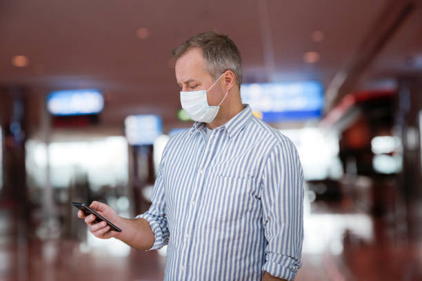 istock Man in protective mask standing in airport hall 1216352138