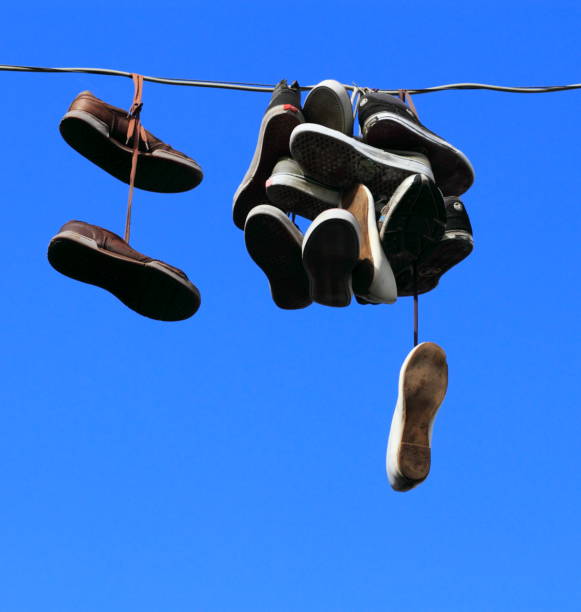 istock Shoes hanging on a line against a blue sky 1216353124