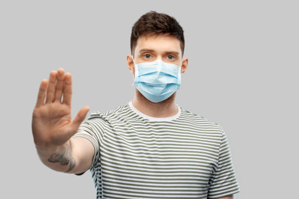 istock man in protective medical mask making stop gesture 1216353697