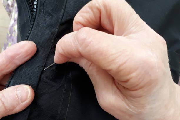 istock hands with sewing needle sew up clothes 1216357968