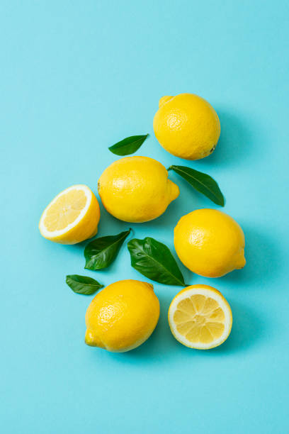 Ripe lemons flat lay with leaves on blue background