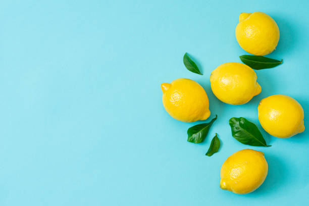 istock Ripe lemons flat lay with leaves on blue background 1216360643