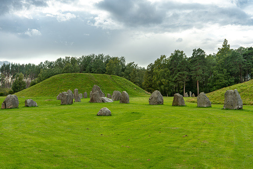 Summer view of an ancient burial ground in Anundshog in Sweden. With rock formations and a large green burial mound