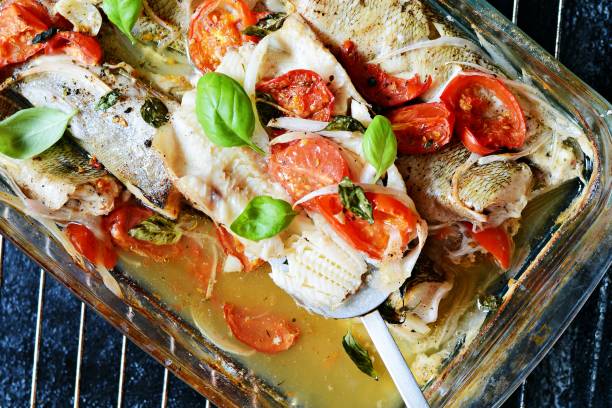 weißfisch (pollock, kabeljau, seehecht) mit tomaten, italienischen kräutern und frischen basilikumblättern in basilikum im eigenen saft gebacken. köstliches mediterranes meeresfrüchte-abendessen. - merluza stock-fotos und bilder