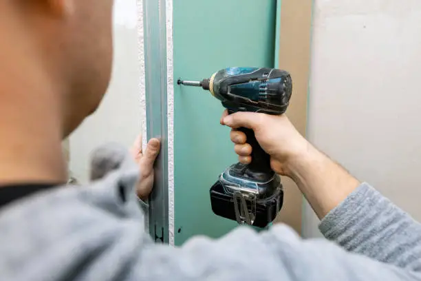 man installing moisture resistant drywall sheets for bathroom bulkhead